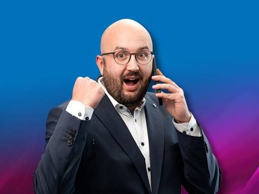 Ein Mitarbeiter der TEN eG mit Brille der ein Telefon am Ohr hat und vor Freude eine Hand zur Faust ballt.