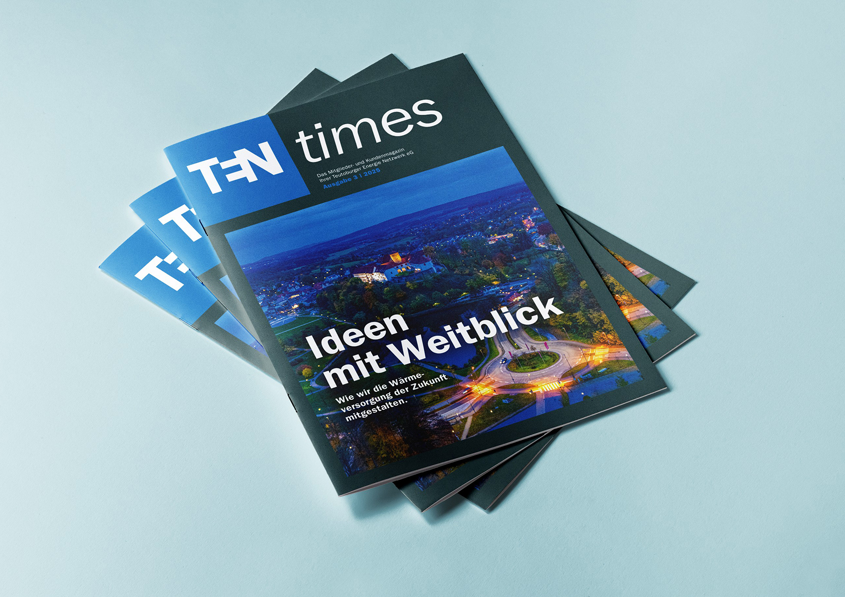 Drei Ausgaben des Mitglieder- und Kundenmagazins TENtimes liegen aufgefächert vor einem schlichten blaugrauen Hintergrund.